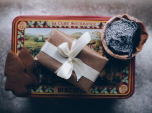 gift wrapped in kraft paper and tied with a ribbon on top of a decorative tin beside a chocolate tart