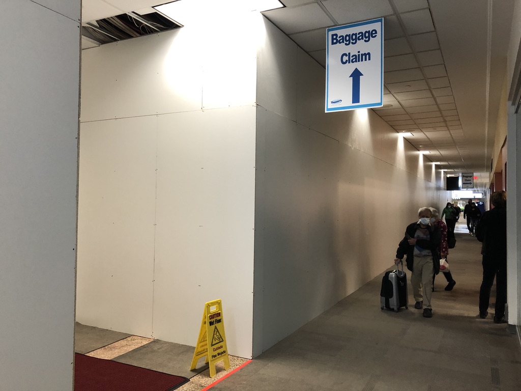 Hallway with dust walls erected and sign pointing to Baggage Claim area